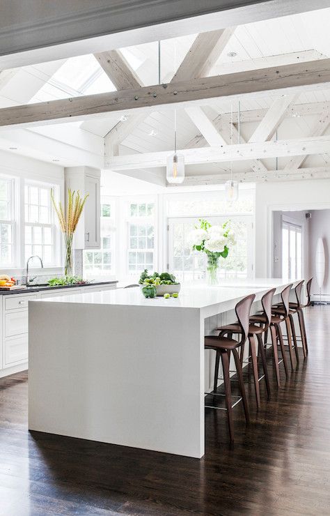 rustic kitchen design is modernized with a sleek white waterfall countertop