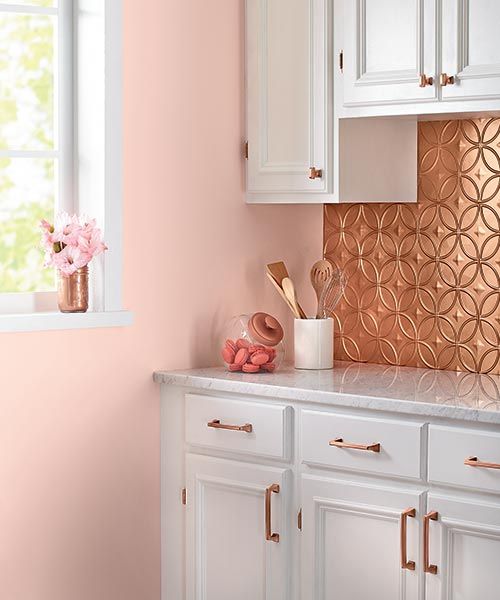 a tin-tile backsplash, matching copper cabinet pulls, and serene pink walls make for a charming kitchen corner