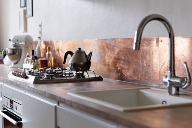 a white kitchen with a low copper kitchen backsplash looks airy and beautiful