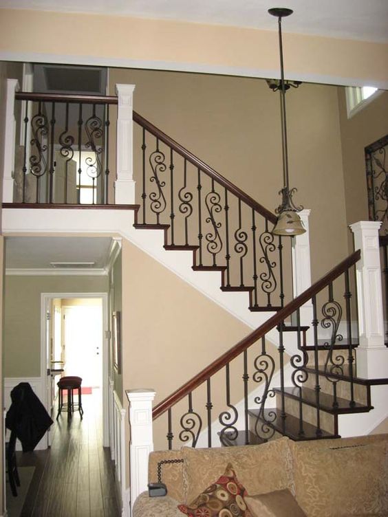 traditional stairs with a wooden handrail and a wrought iron balustrade with a chic pattern