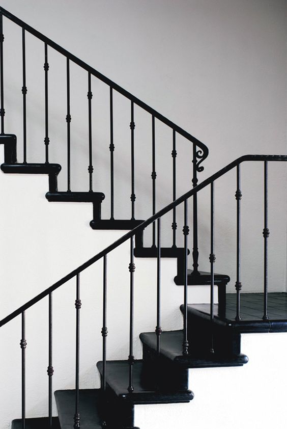 black and white space with a stylish staircase with black iron handrail and balustrade