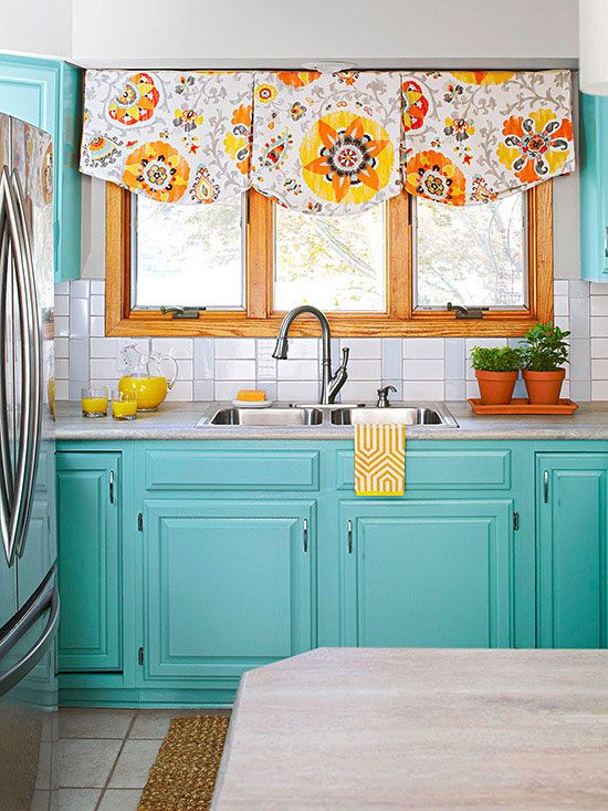 colorful blue cabinets and bold floral curtains make the kitchen spring-like