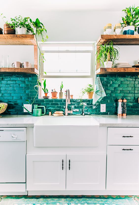a brick backsplash painted in emerald color echoes with greenery