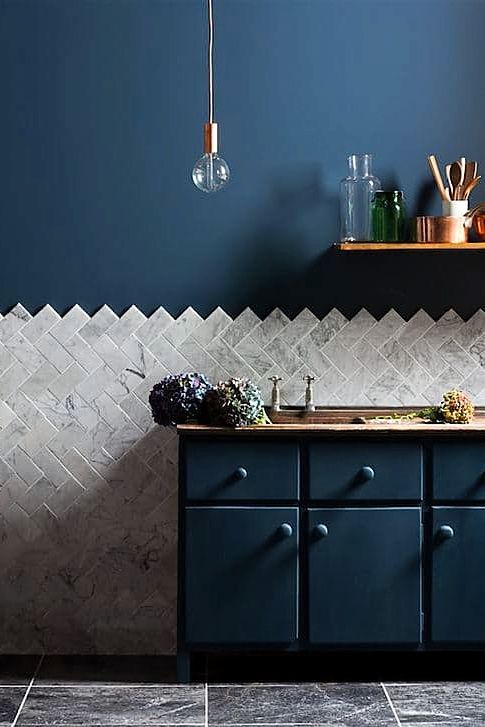 navy cabinets and a wall, marble tiles clad in a chevron pattern