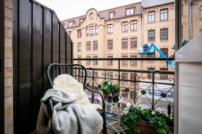 small scandinavian balcony There's a small balcony with potted greenery and a forged chair covered with blankets