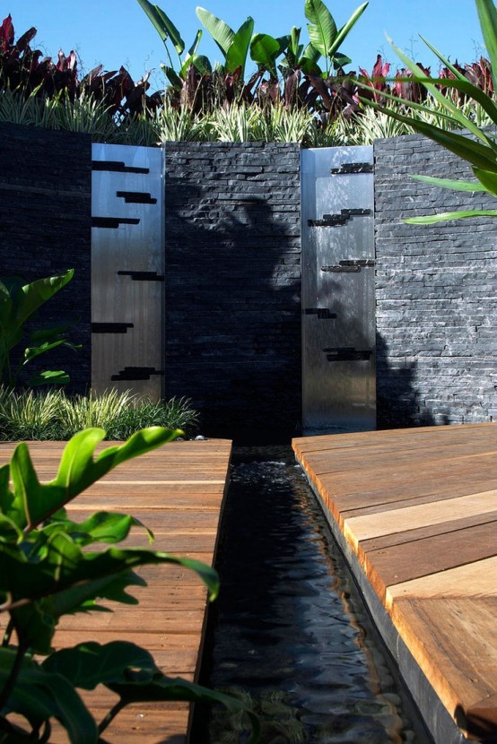 Contemporary metal water walls framed in black stone.