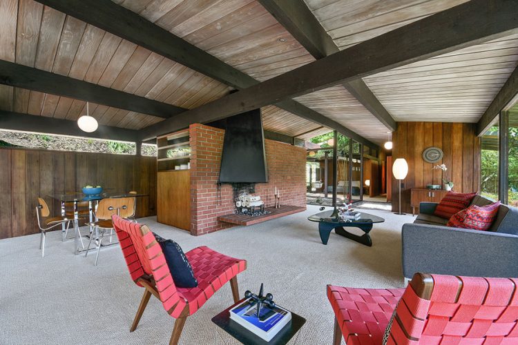 living room with mid century moderm furniture and a brick fireplace wall