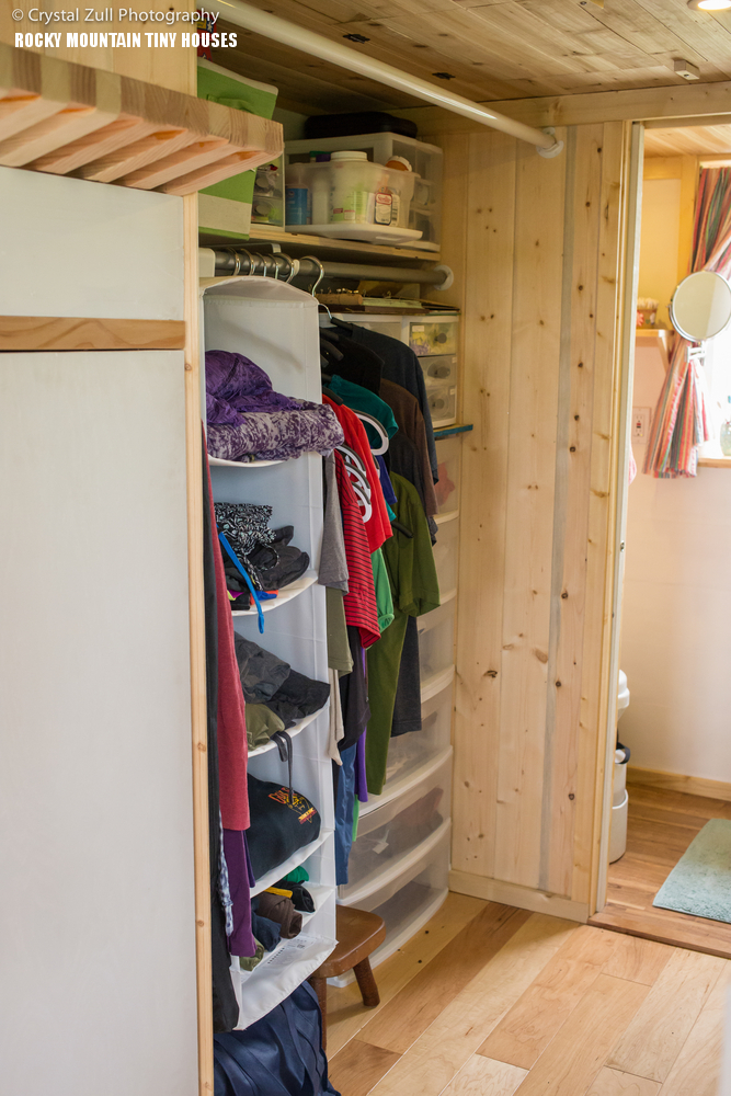 There's a compact walk-in closet with lots of shelves and cubbies