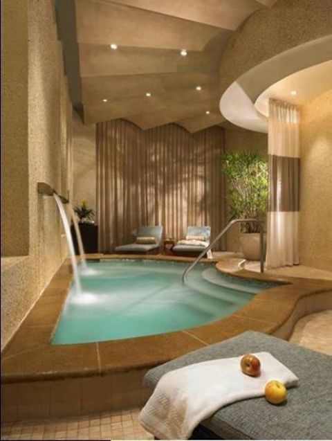 tiny indoor pool with two waterfalls and a tiled deck