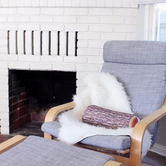 grey Poang chair with faux sheepskin and a log pillow