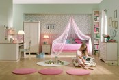 a hot pink and neutral kid’s room with pink paneling, pink rugs and cool white furniture, floral wallpaper and a gallery wall