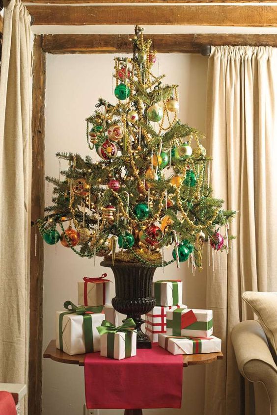 a bright vintage inspired Christmas tree in an urn, decorated with pink, emerald and orange ornaments and beaded garlands