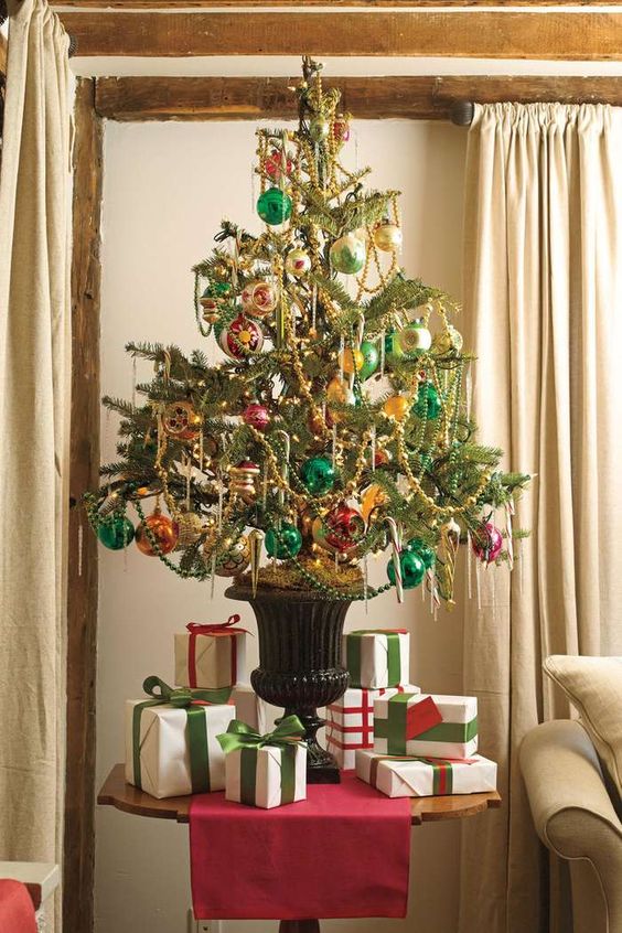 a bright vintage-inspired Christmas tree in an urn, decorated with pink, emerald and orange ornaments and beaded garlands