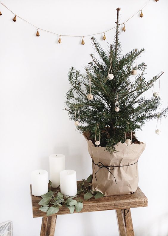 a minimalist Nordic tabletop Christmas tree decorated with wooden beads and wrapped into kraft paper is simple but cool