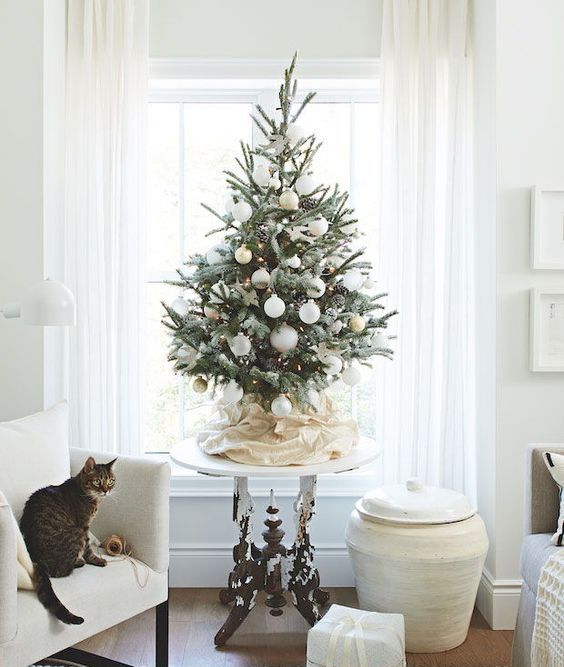 a modern snowy Christmas tree with lights, pinecones and white and gold ornaments looks beautiful and chic