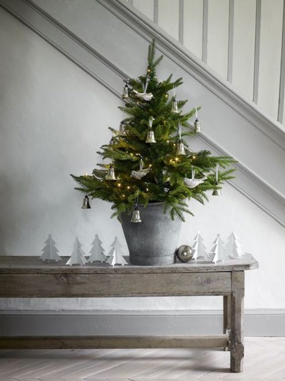a rustic tabletop Christmas tree in a bucket, with lights, bells and birds is a pretty and cool idea for a Nordic space