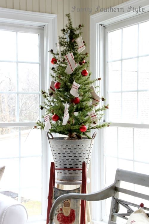 a small Christmas tree decorated with little pinecones, red ornaments and tiny stockings looks rustic and pretty