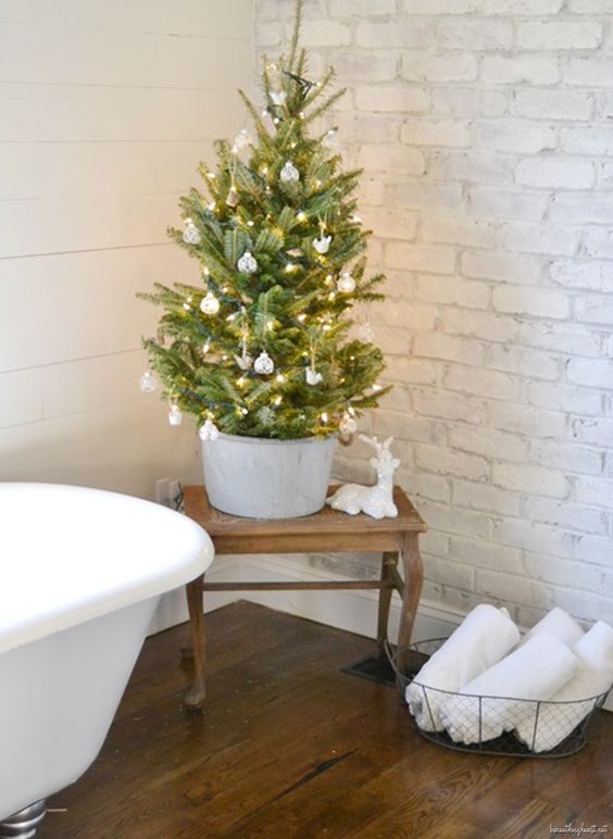 a small Christmas tree in a galvanized bucket, with white and silver ornaments and lights is a pretty idea