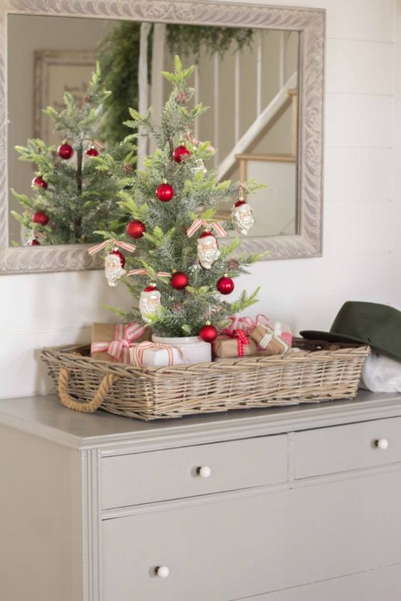 a tabletop Christmas tree decorated with red ornaments and Santa Claus heads is a fun and cool idea with a touch of vintage