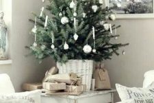 a tabletop Christmas tree in a whitewashed basket, with white and silver ornaments is a lovely idea for a Scandinavian space