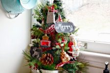 a tiny tabletop Christmas tree decorated with pinecones, berries, signs and kitchen stuff is a fun and cheerful idea to rock