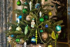a vintage glam Christmas tree in a copper urn, with emerald, navy and gold ornaments, beads and colorful icicles is a cool idea