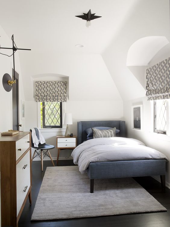 a cozy mid-century modern teen room with a blue upholstered bed, a dresser, printed textiles, a small nightstand and a chair