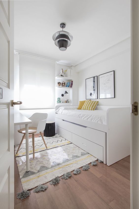 a neutral Scandinavian bedroom with a bed with storage, a desk and a chair, built-in shelves and a printed rug