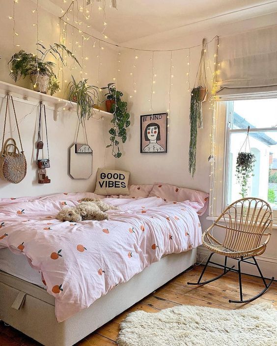 a pretty teen room with a storage bed, a shelf with lots of potted plants and lights hanging over the bed, pretty bedding and art