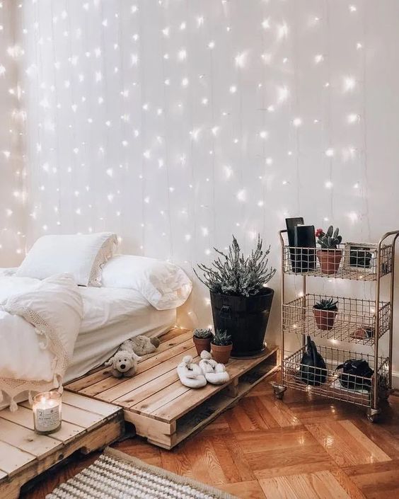 a relaxed boho teen bedroom with a pallet bed, a metal layered shelf, neutral bedding, potted plants