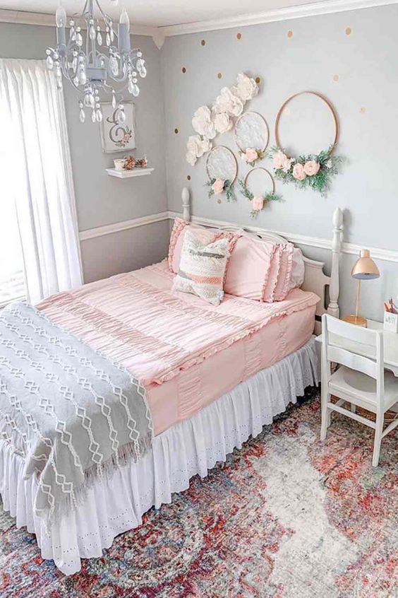 a romantic vintage teen bedroom with light blue walls, vintage neutral furniture, wreaths with blooms, a blue crystal chandelier and pastel bedding