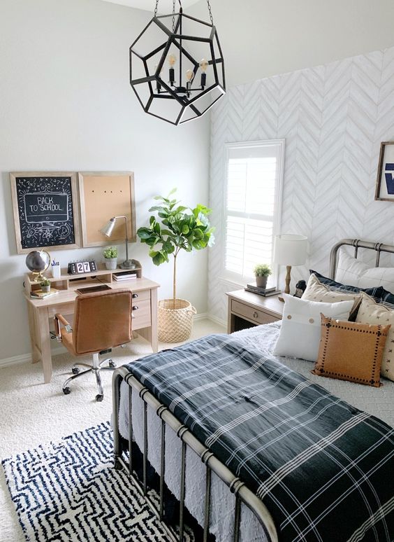 a stylish farmhouse teen room with a metal bed, lots of pillows, a small desk and a leather chair plus a faceted pendant lamp