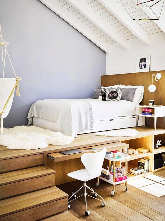 a teen room with a raised platform bed, a built-in desk and storage compartments, a white chair and a suspended chair