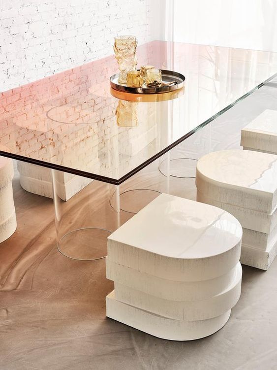 a beautiful modern dining table with glasses holding the ombre glass tabletop and eye catchy stacked stools for a modern space