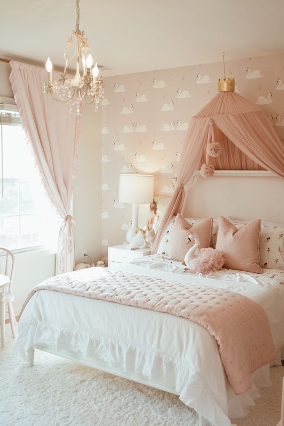 a blush and white girl's bedroom with pink flamingo wallpaper, a white bed with pink and white bedding, a pink canopy and a crystal chandelier