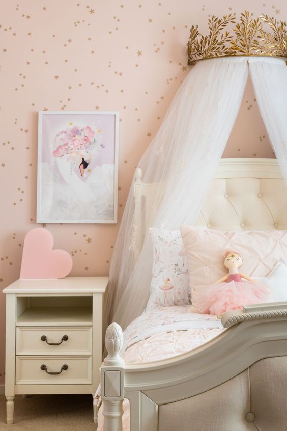 a blush princess room with a spotted accent wall, a white bed and a nightstand, a crown with a canopy is a lovely idea