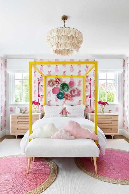 a bright girl's room with bright pineapple print wallpaper, a neon yellow canopy bed, chic nightstands, pink rugs and pink pillows