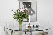 a chic modern round dining table with a steel framing and a glass tabletop looks cool and glam