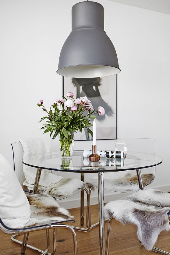 a chic modern round dining table with a steel framing and a glass tabletop looks cool and glam