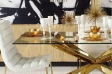 a glam black, white and gold dining room with a chic table with a glass tabletop and a gold base, white upholstered chairs and a crystal tube chandelier