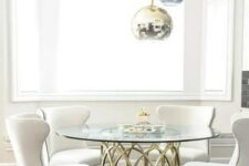 a glam dining space with metallic sphere pendant lamps, a brass table base and a round tabletop, comfy cream chairs