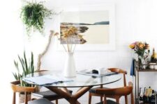 a mid-century modern inspired dining table with a sculptural wooden base and a round glass tabletop, matching chairs with leather upholstery