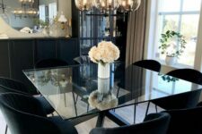 a modern dining table with black legs stacked and a square glass tabletop, matching black chairs and a tiered chandelier for a modern dining room