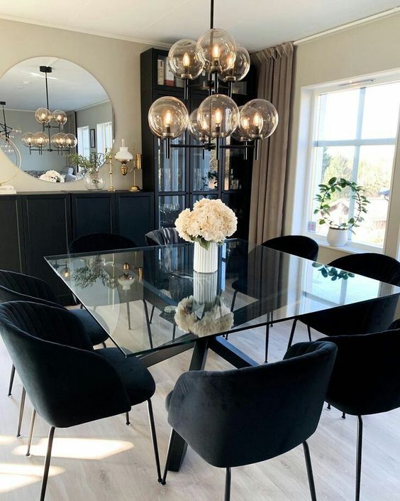 a modern dining table with black legs stacked and a square glass tabletop, matching black chairs and a tiered chandelier for a modern dining room