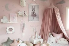 a pink girl’s bedroom with a pink accent wall, neutral furniture, neutral bedding, a pink canopy, a gallery wall and a fluffy pendant lamp