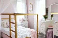 a shabby chic pink girl’s bedroom with pink walls, gold canopy beds with pink and white bedding, a vintage vanity and a pink stool
