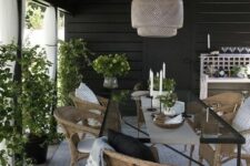 a stylish modern dining table with a black frame and a glass tabletop, woven chairs, neutral and contrasting textiles, a woven pendant lamp
