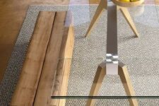 a table with a metal frame and wooden legs, a clear glass tabletop and a piece of wood as a bench for both a modern and rustic look
