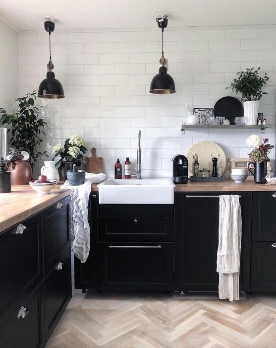 a Nordic kitchen with black cabinetry, butcherblock countertops, black pendant lamps and potted plants to refresh it