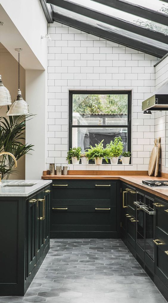 a chic modern farmhouse kitchen with black shaker cabinets, butcherblock countertops and a white marble one on the island, a glazed ceiling for natural light